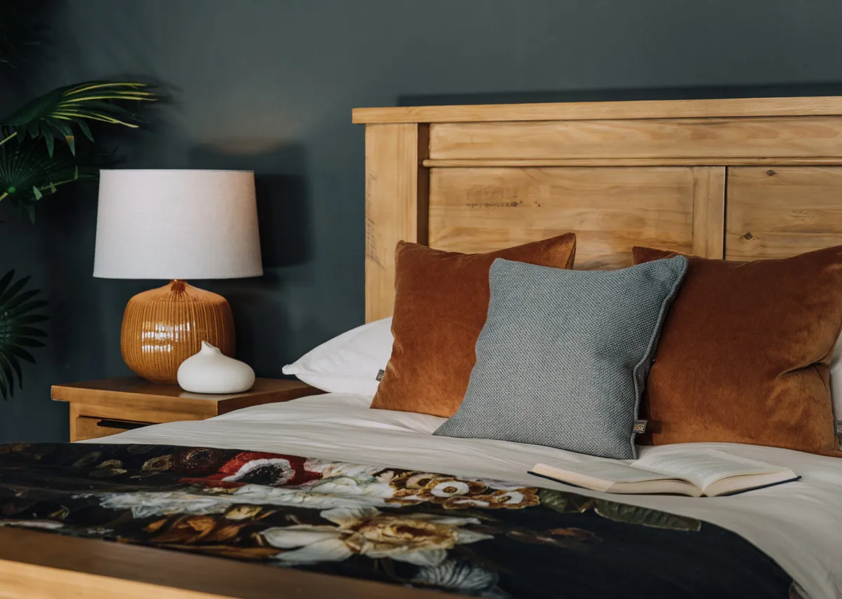 A close up showing the interior side rail and wooden slats of a light brown wooden bed frame.