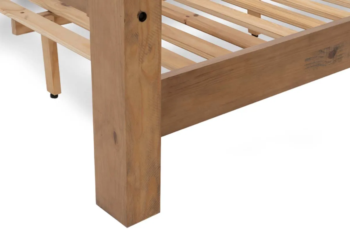 A side view of a light brown wooden bed frame with a headboard and footboard holding a white mattress.