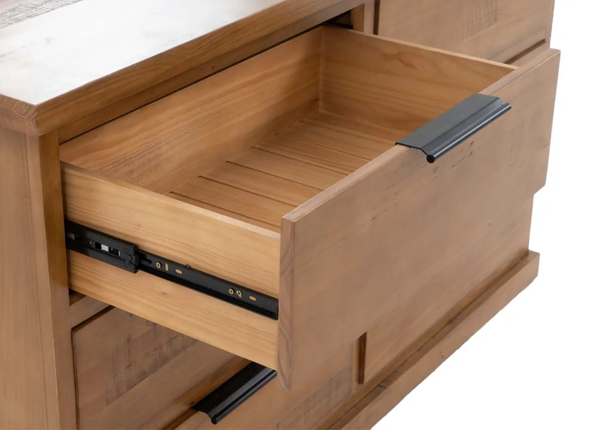 A side view of a light brown wooden dresser with three drawers on the right and a rectangular mirror standing on top.