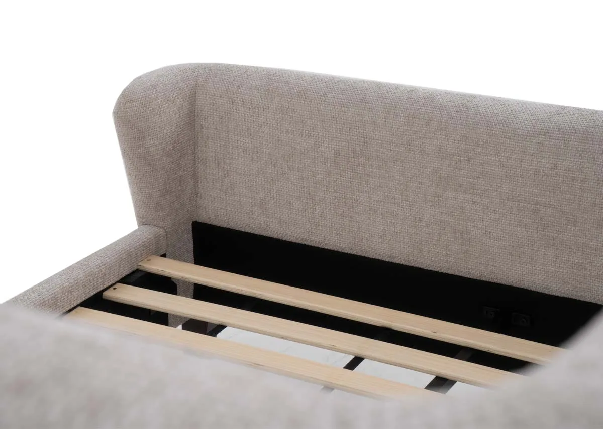 A beige fabric bedframe with winged headboard and dark brown legs. Closeup of high footboard.