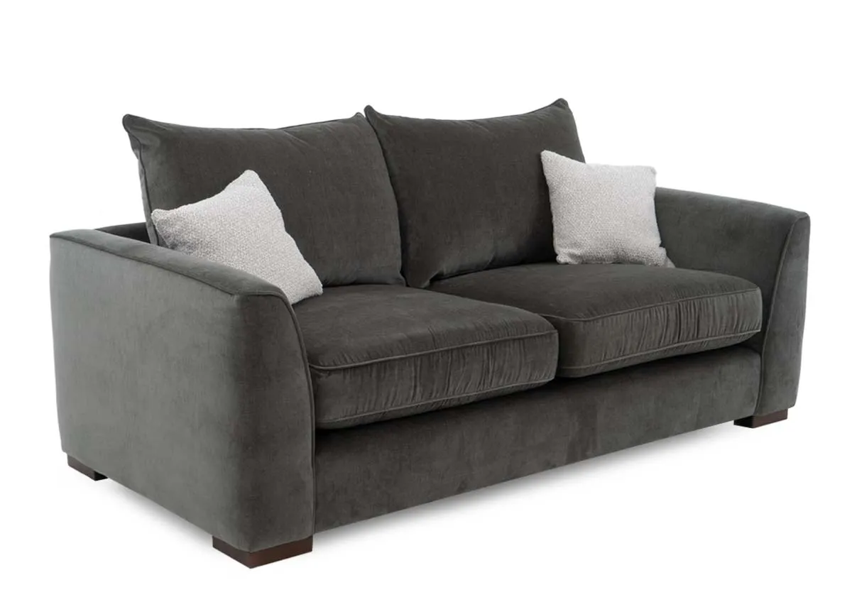 A 3 seater sofa in spruce green fabric from EZ Livings Lucius range. Angled view of 2 cream scatter cushions