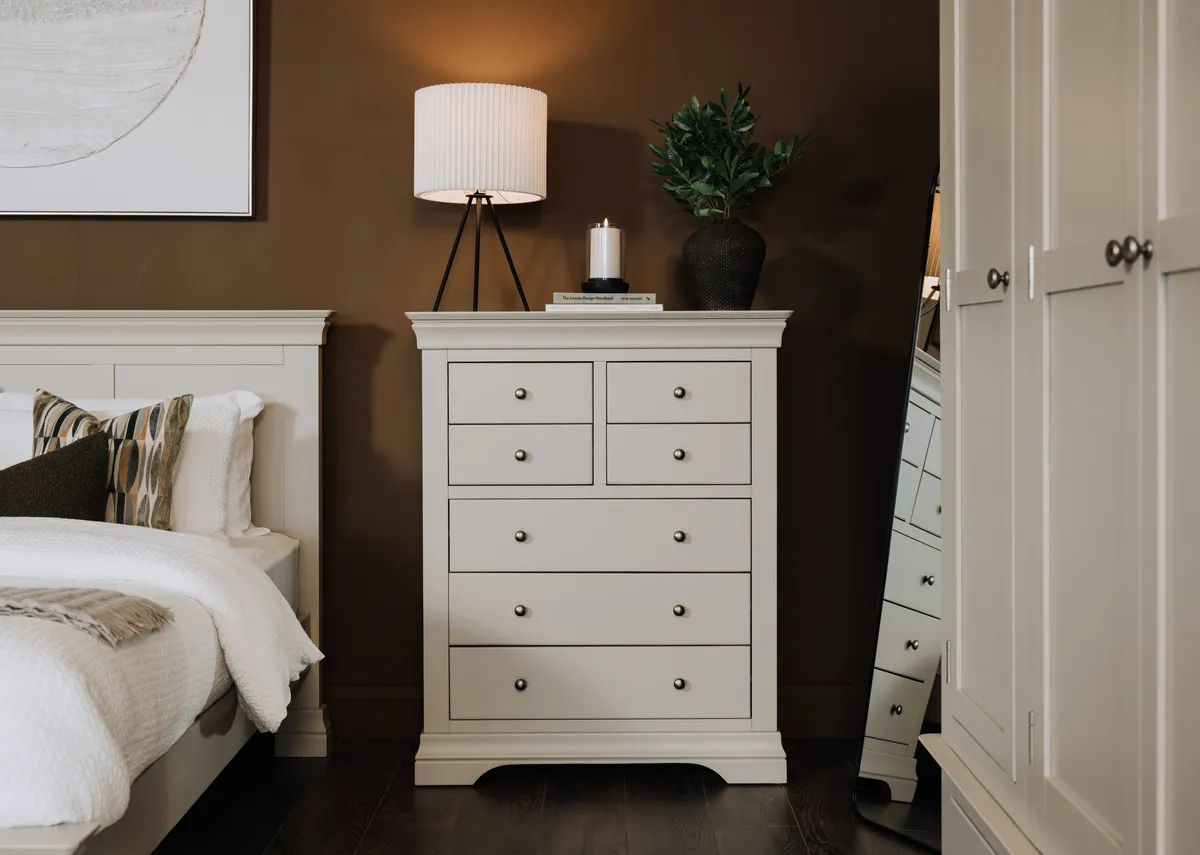 A lifestyle image of the Dove taupe chest of drawers with Starlette lamp and Vance mirror.