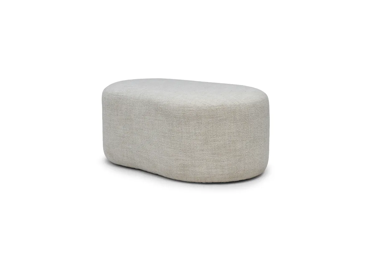 A pebble shaped footstool in soft cream boucle from EZ Livings Carnaby range. Angled view