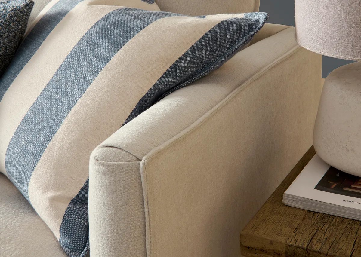 A beige linen rhf corner chaise with oak feet from the Vogue range. Front view of foam seat cushions and blue stripe cushions.