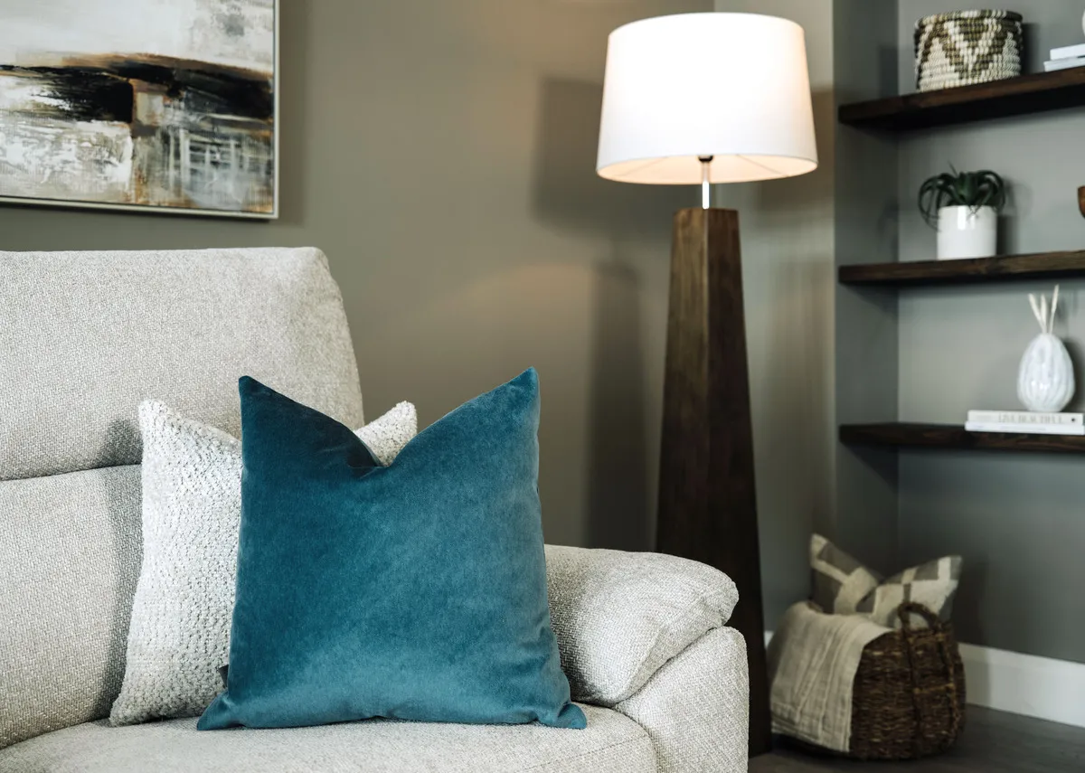 A lifestyle image of the Richelle teal cushion on a grey sofa with Fauna lamp.