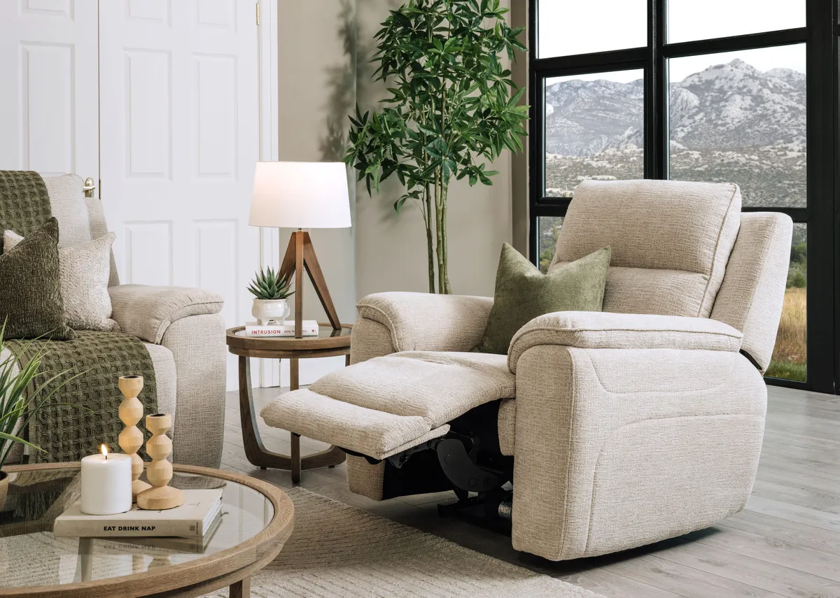 A lifestyle image of the Aura beige fabric recliner fully out with Alexis table and Glenveagh table lamp.