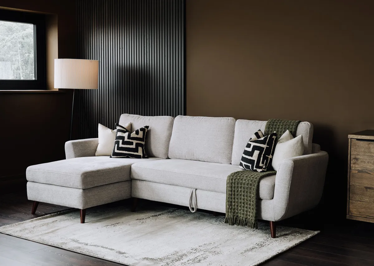 A grey fabric 3 seater sofa chaise from EZ Livings Sasha range. Closeup on pull tage to front of sofa where can be extended into a bed.