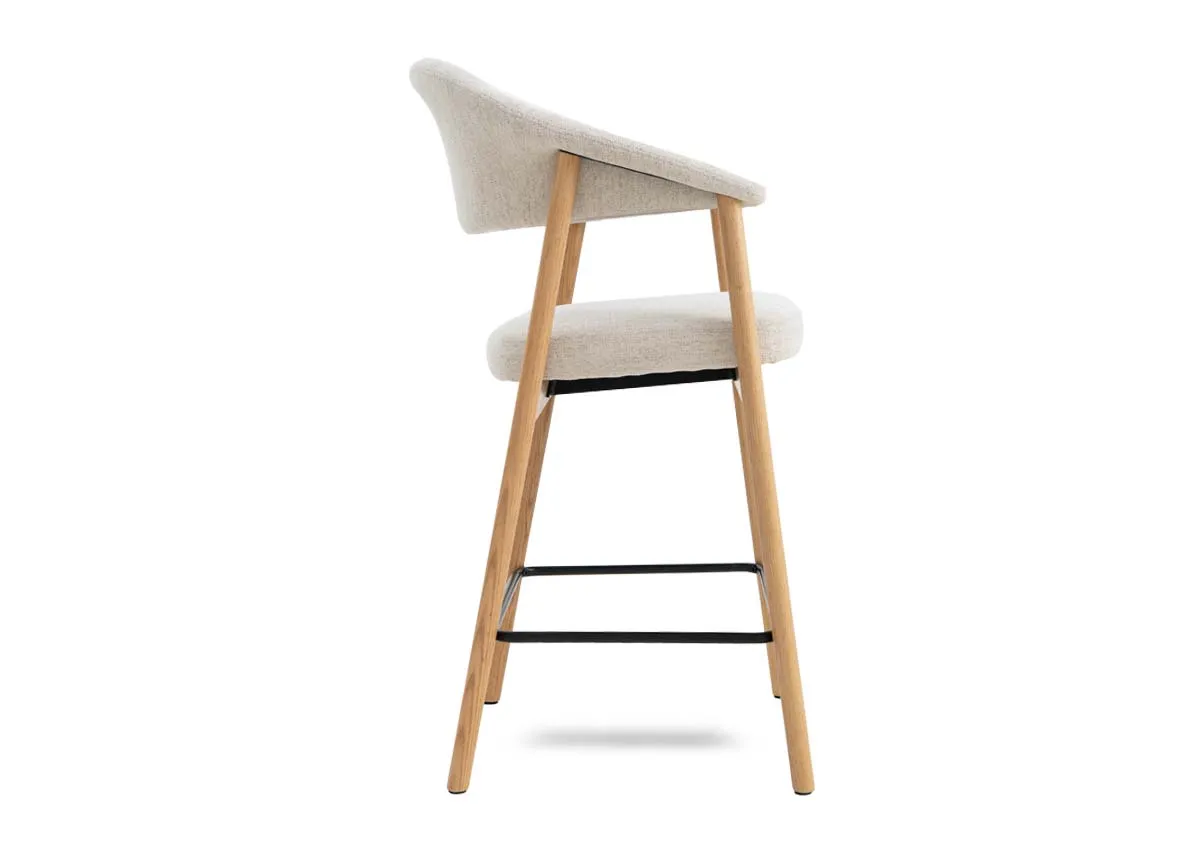 A natural oak framed counter stool with cream fabric backrest and padded seat from EZ Livings Elk range. Side view of metal foot wrung