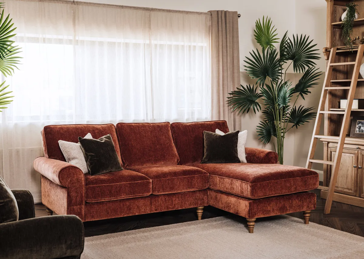 A lifetsyle image of the Cotswold corner sofa with green cushions and the Iona Bookcase