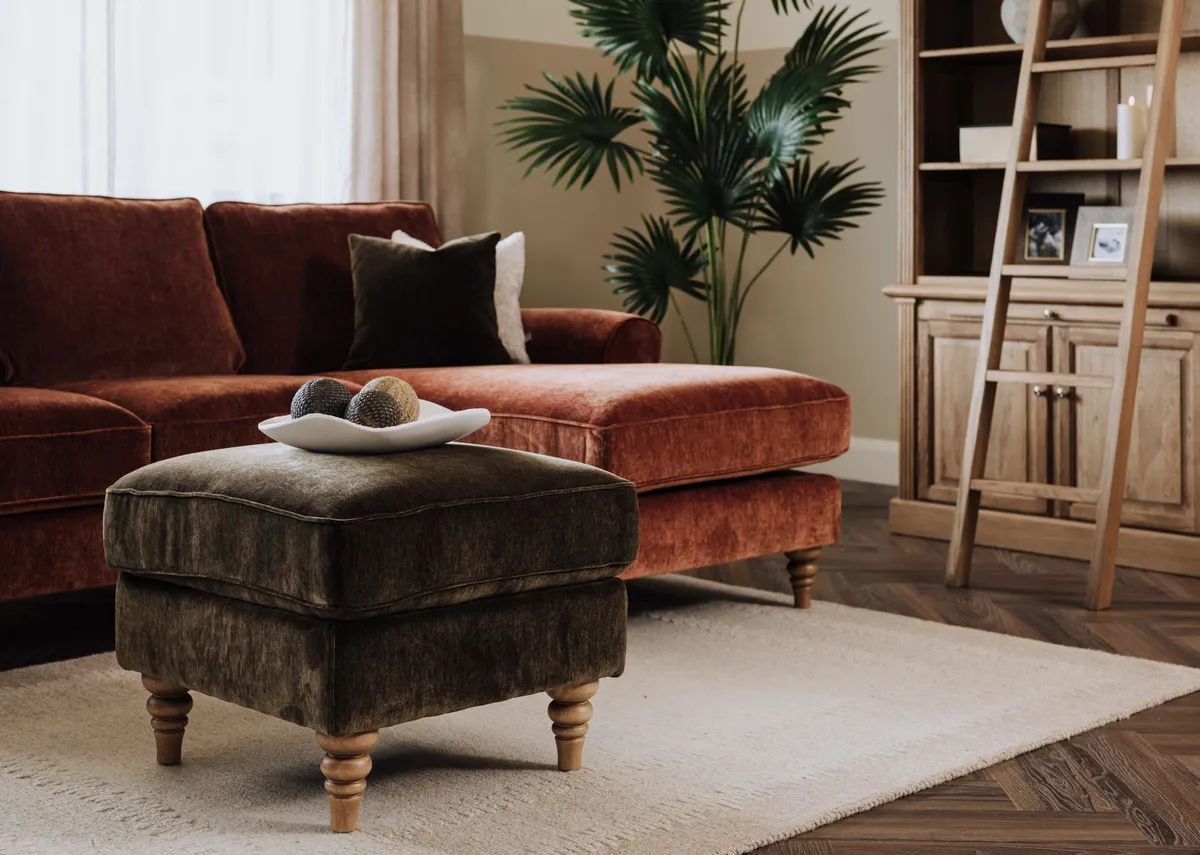 A lifestyle image of the Cotswold footstool in green with rust corner chaise and Iona bookcase.