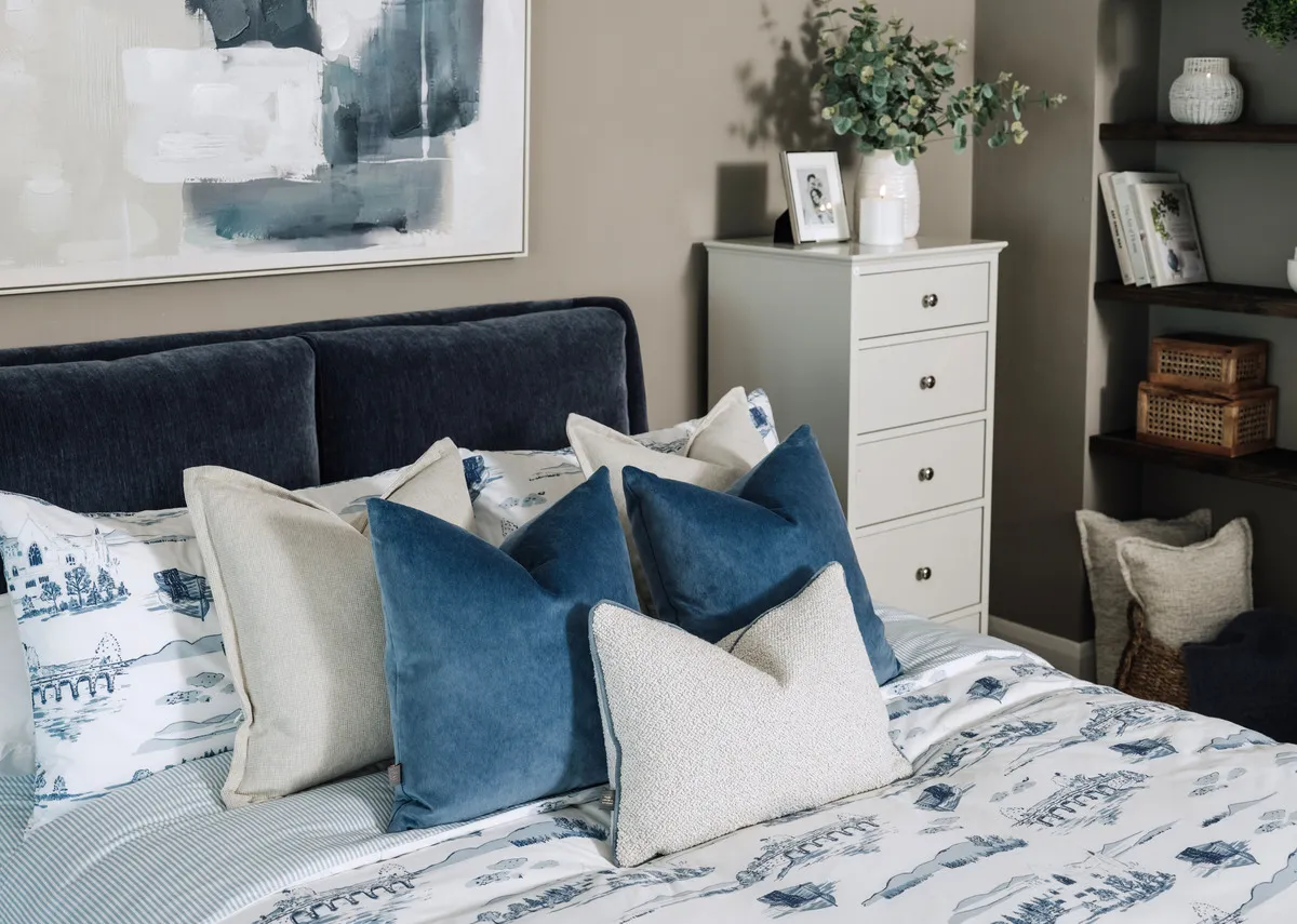 A lifestyle image of the richell and earthbound cushion with a selection of cushions on the Comfy blue bedframe.