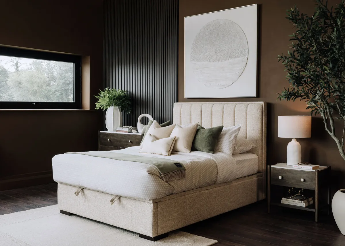 A beige fabric ottoman bed from EZ Livings Liberty range. Angled view of base lifted to reveal storage space