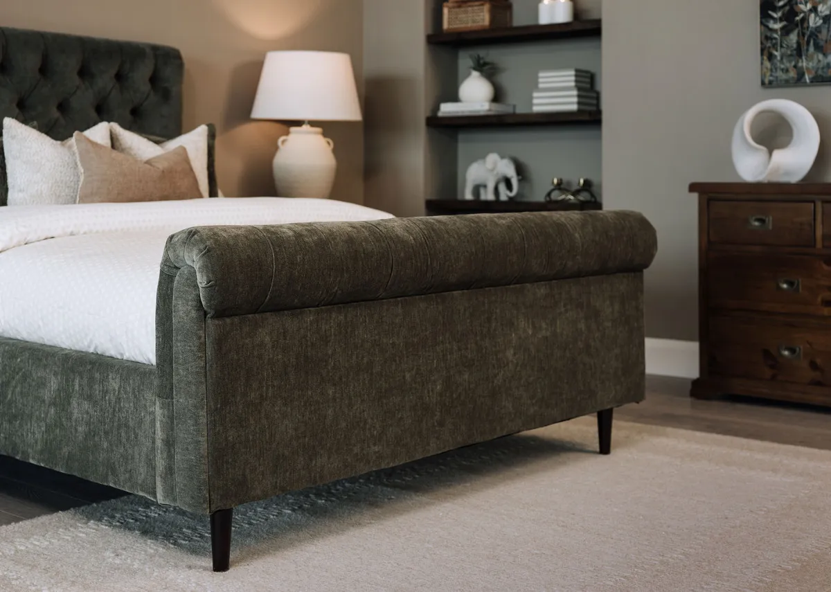 A lifestyle image of the Sofia green bedframe with a closeup on the scroll footboard detail.