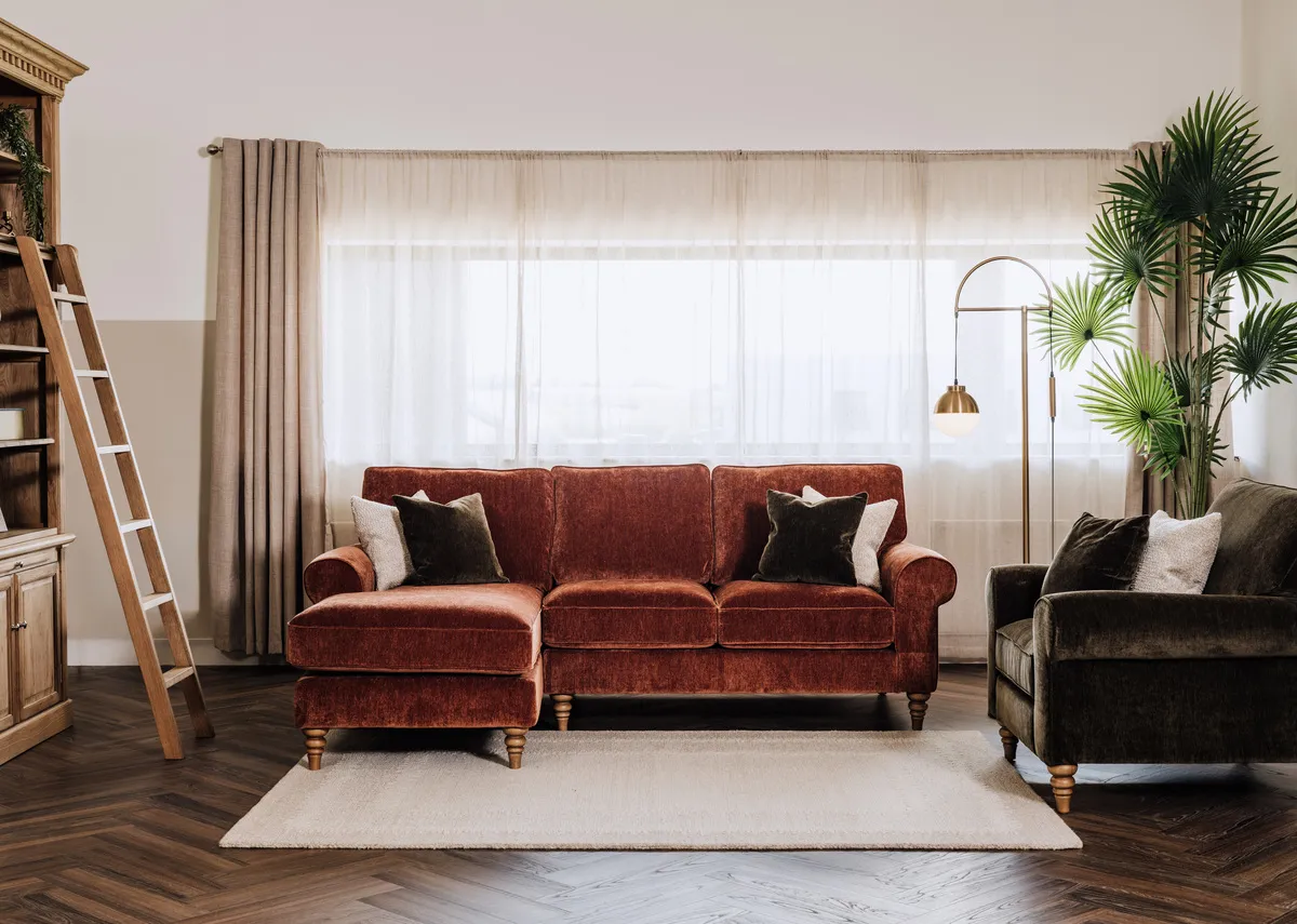A lifestyle image of the Cotswold corner chaise with Iona bookcase and Green cotswold armchair.