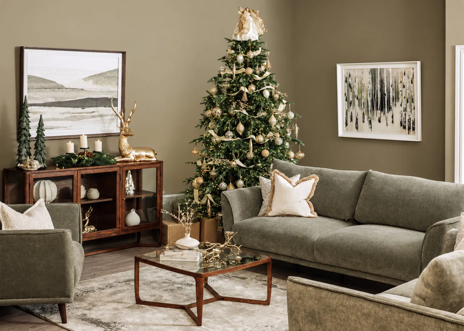 A lifestyle image of the Angel tree topper in gold on the Rockefeller tree with Boutique green sofas.