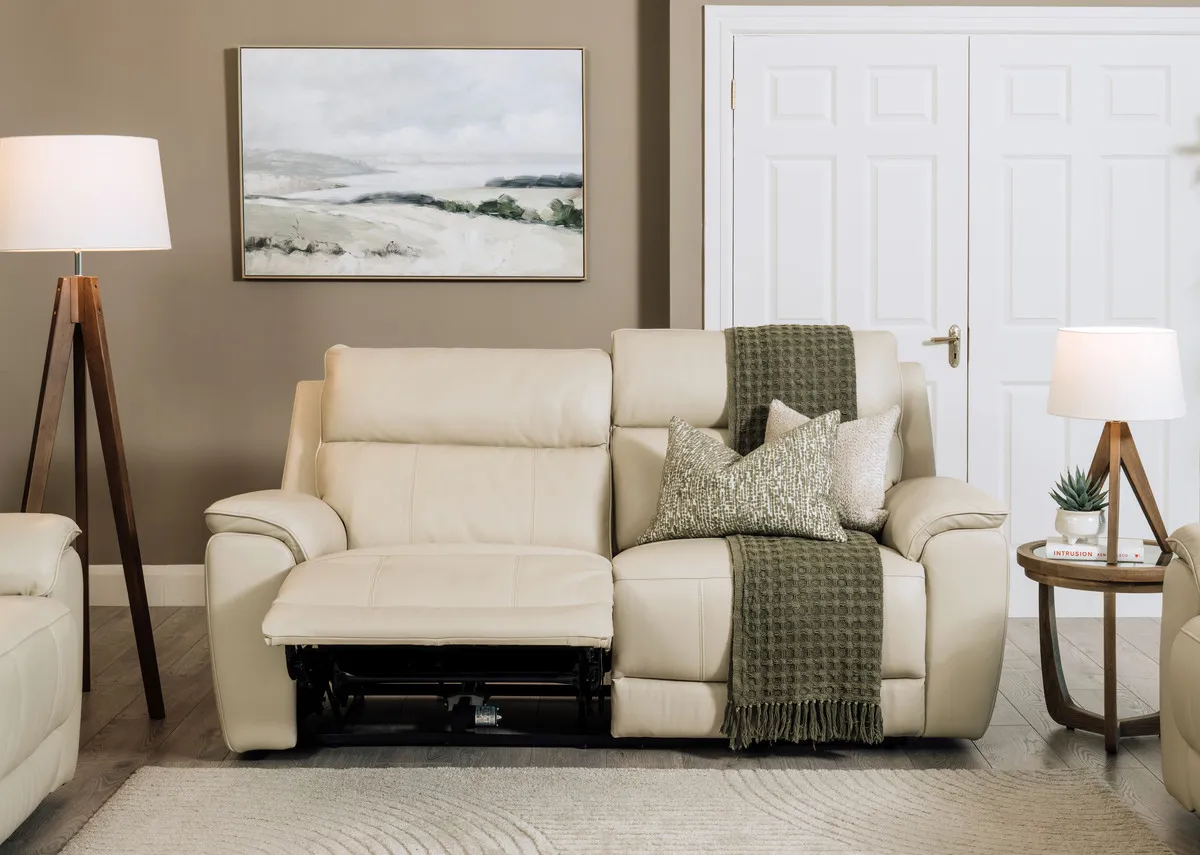 A lifestyle image of the Aura leather 3 seater reclined with Alexis tables and Glenveagh lamps.