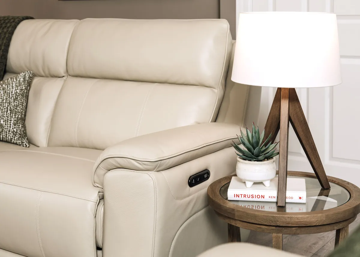 A lifestyle image of the Aura leather 3 seater with a closeup on the padded armrest and remote.