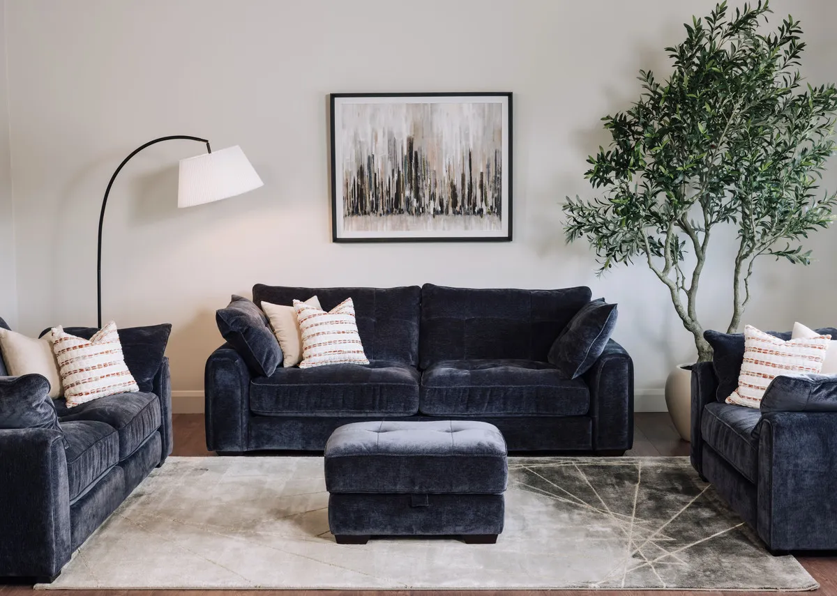 A lifestyle image of the Darcy denim 2.5 seater 2 seater cuddler and footstool with Toko tables and Urban silence picture