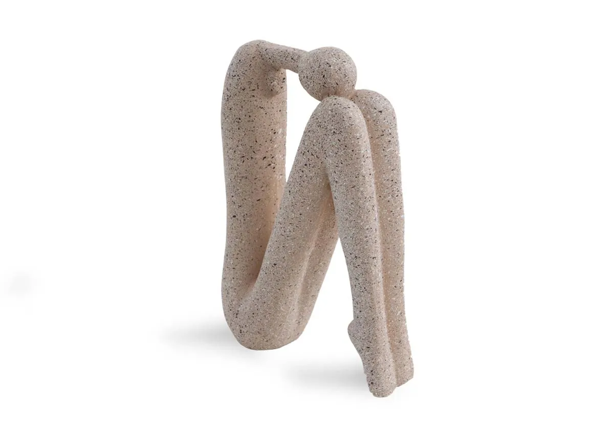 A beige stone human ornament of a head resting on knees pose.