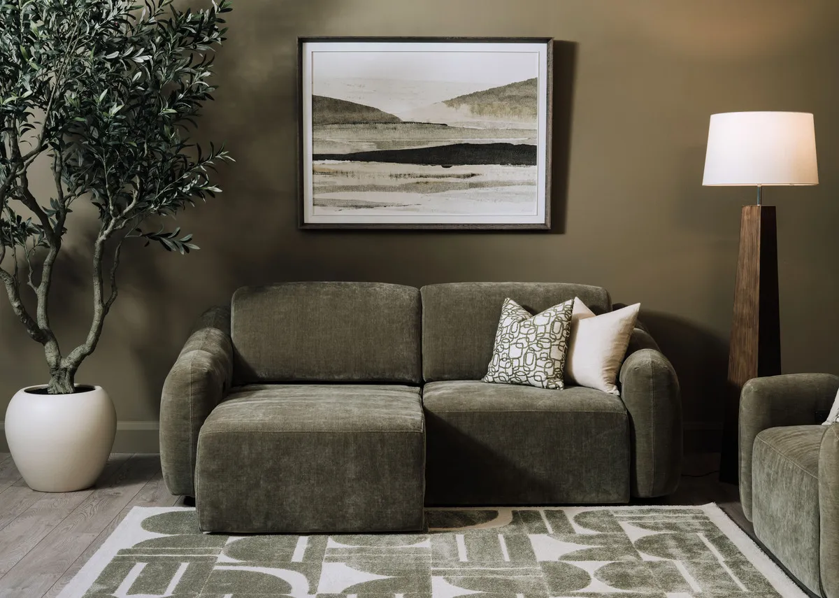 A lifestyle image of the Eleanor green 2 seater with left side as a chaise with Morning Haze painting and Eleanor armchair.