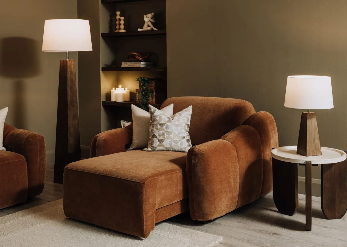 A lifestyle image of the Eleanor rust armchair in reclining mode with Kira tables.