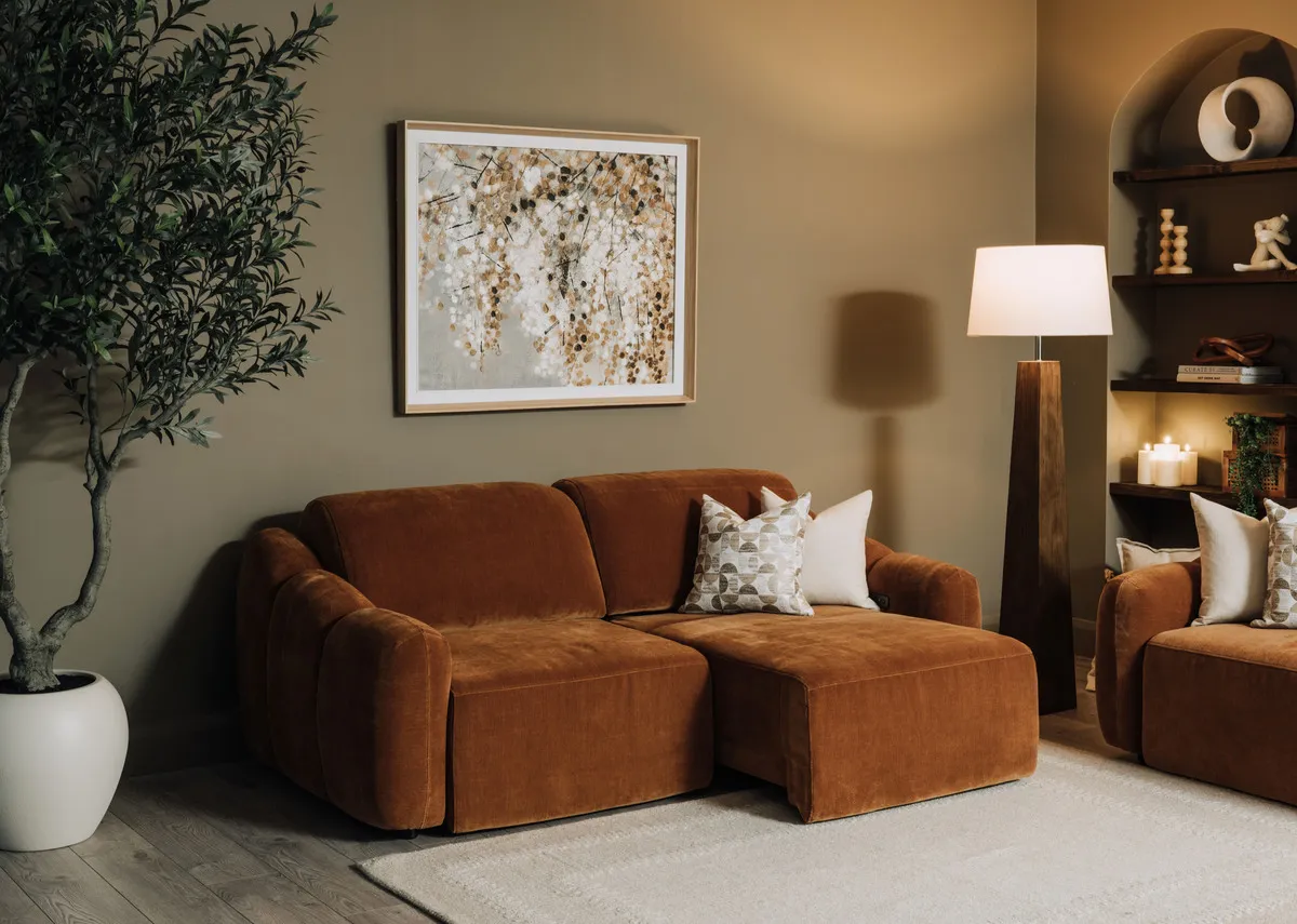 A lifestyle image of the Eleanor rust 2 seater with left side as a chaise with Bliss painting and Eleanor armchair.