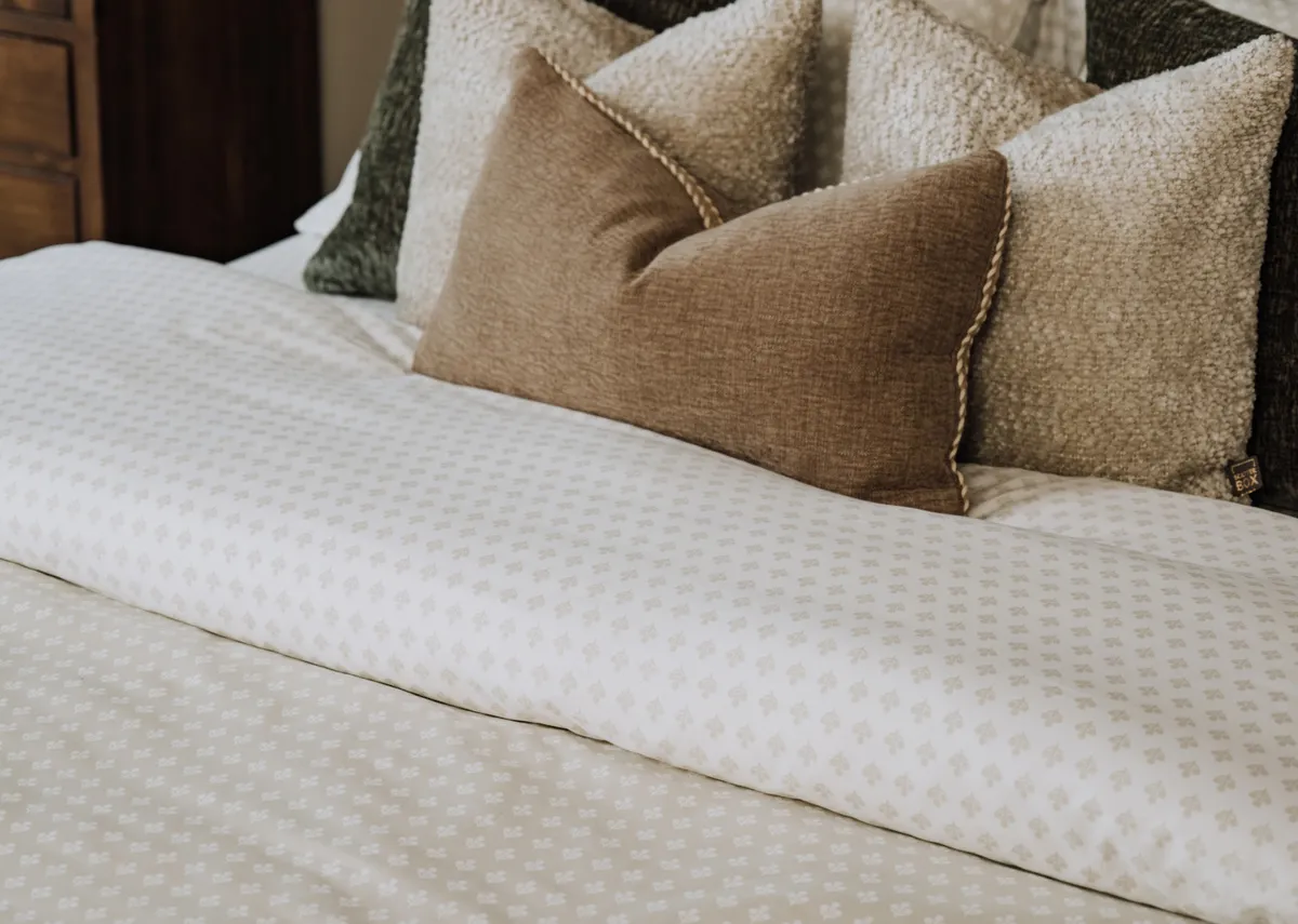 A lifestyle image of the Foxford Mia duvet set on the Sofia bed with a selection of cushions.