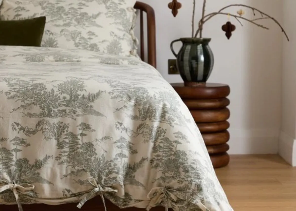 A lifestyle image of the Eve toile duvet set on a wooden bed.