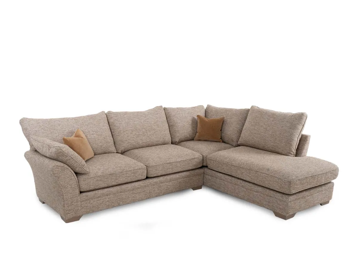 A beige fabric corner sofa with chaise on left from EZ Living Furnitures Strata range. Angled view with 2 gold scatter cushions.