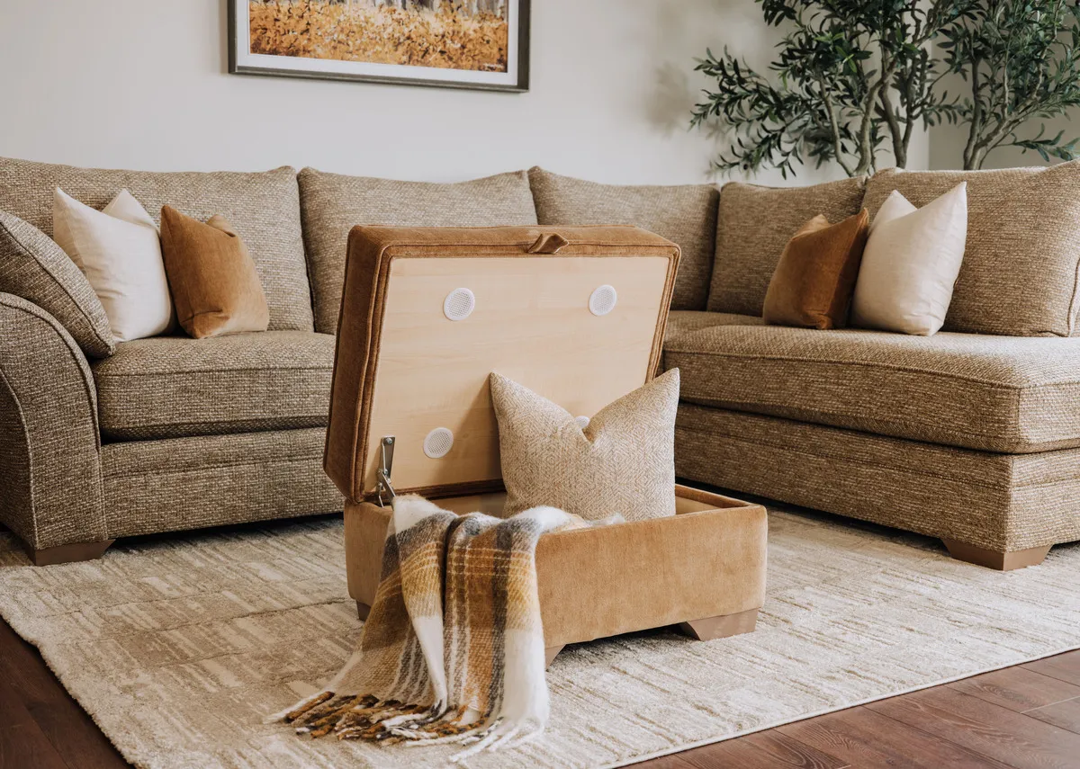A lifestyle image of the Strata footstool open with a blanket inside with the corner chaise and Drift rug.
