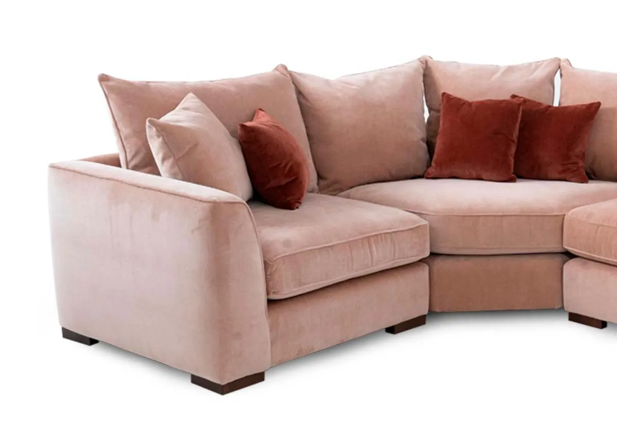 An RAF pink fabric corner sofa with rust cushions from Lucius range. Closeup of corner and arm finish.