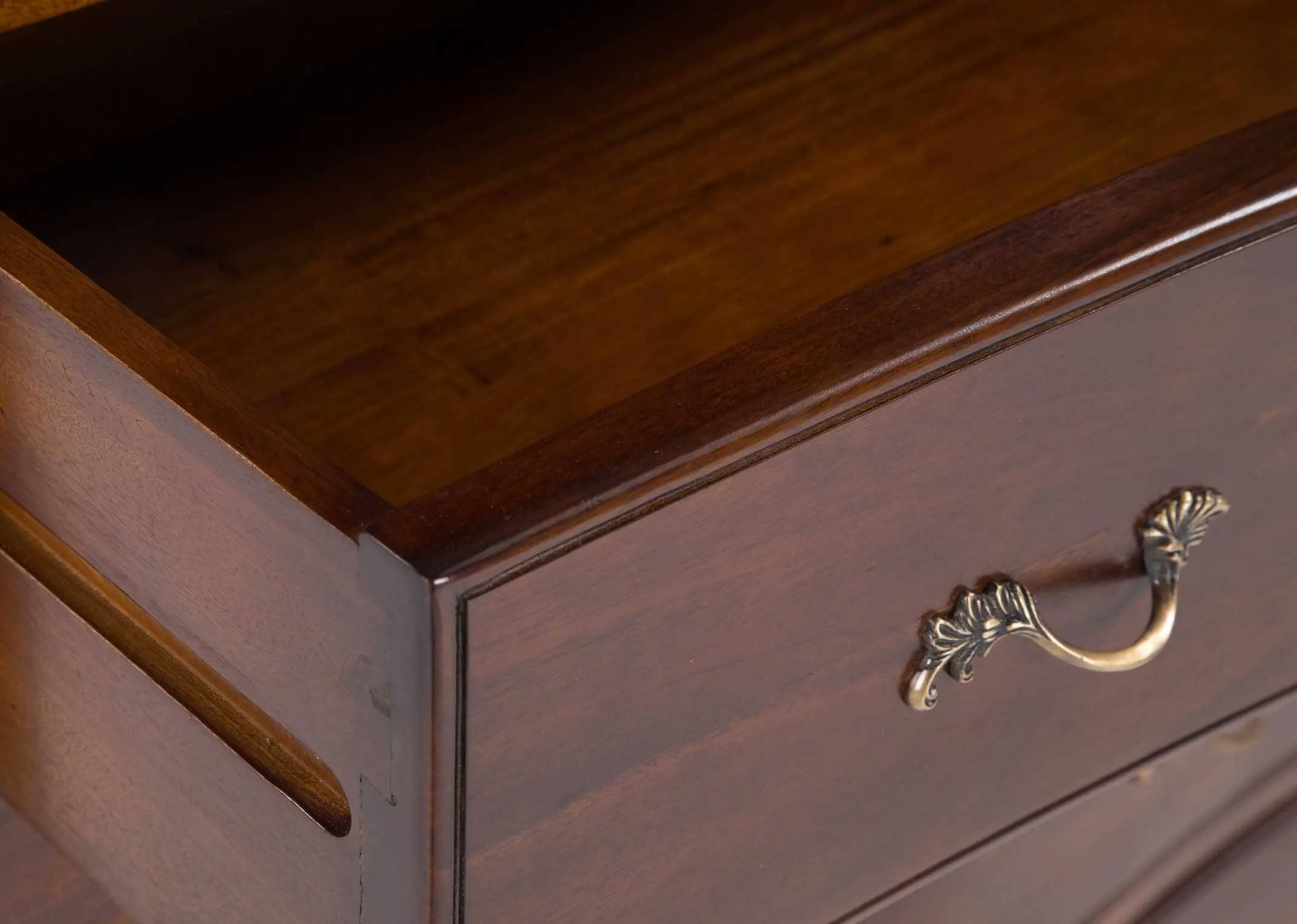 A close up image showing the corner trim of the Lyon 6 drawer mahogany chest.
