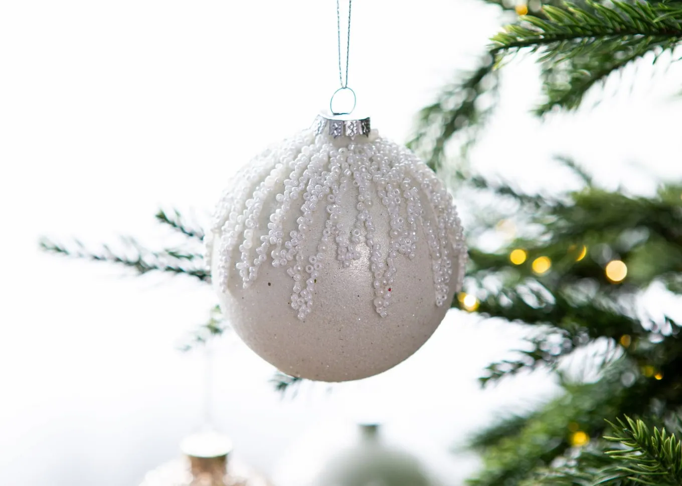 A lifestyle image of the Holly Jolly Bauble on a Christmas tree.