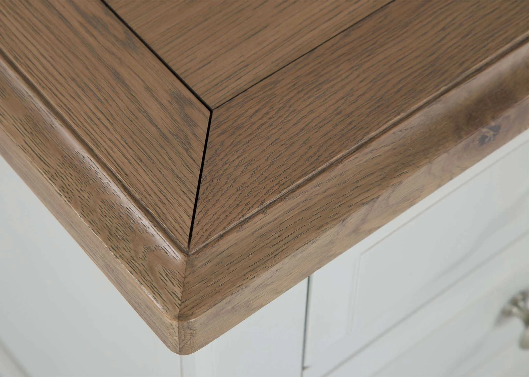 Detailed view of top of three-drawer grey oak bedside locker with light-coloured wooden top Georgia