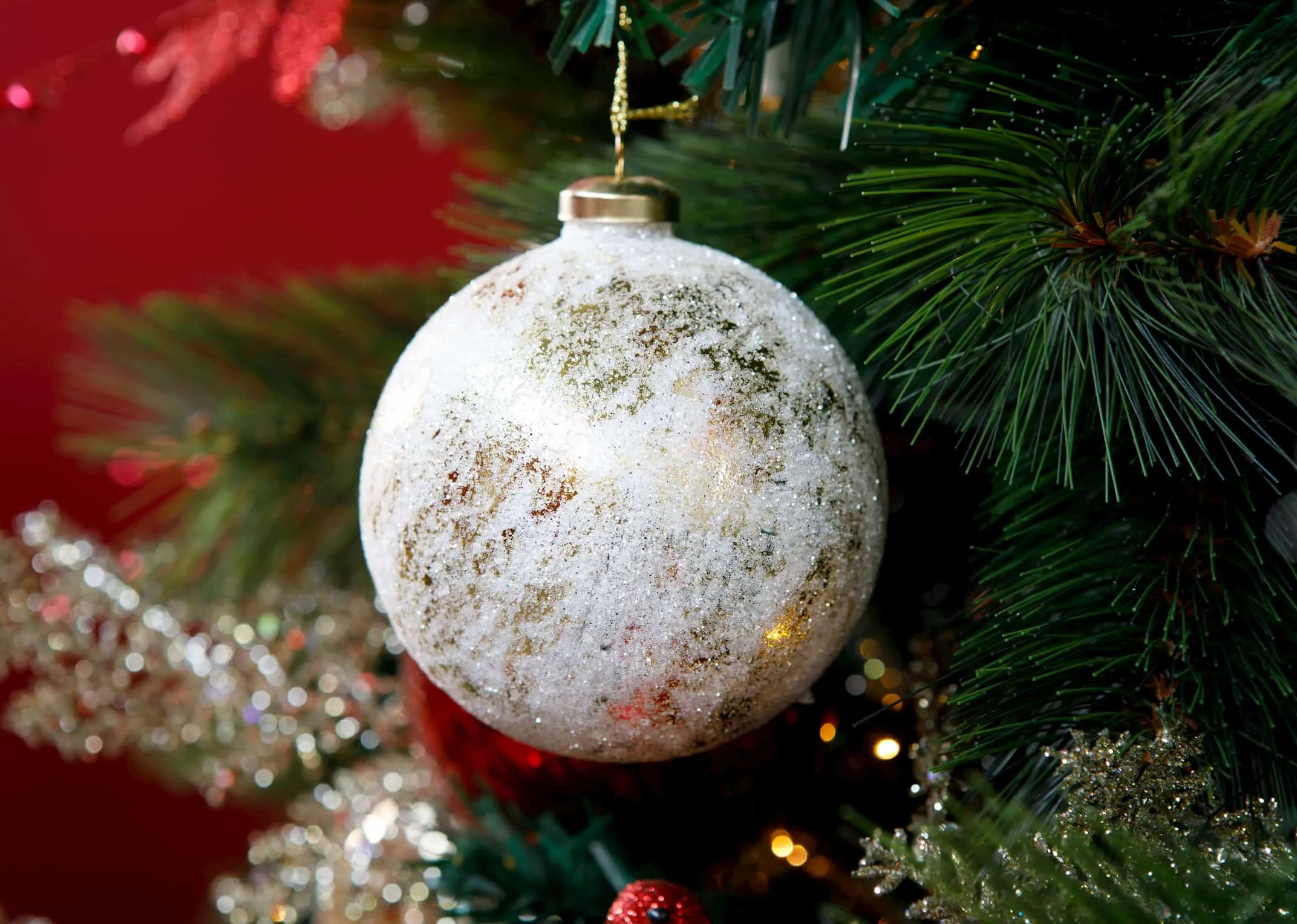 A lifestyle image of the Gold glass bauble on a Christmas tree with gold themes from EZ Living Furniture.