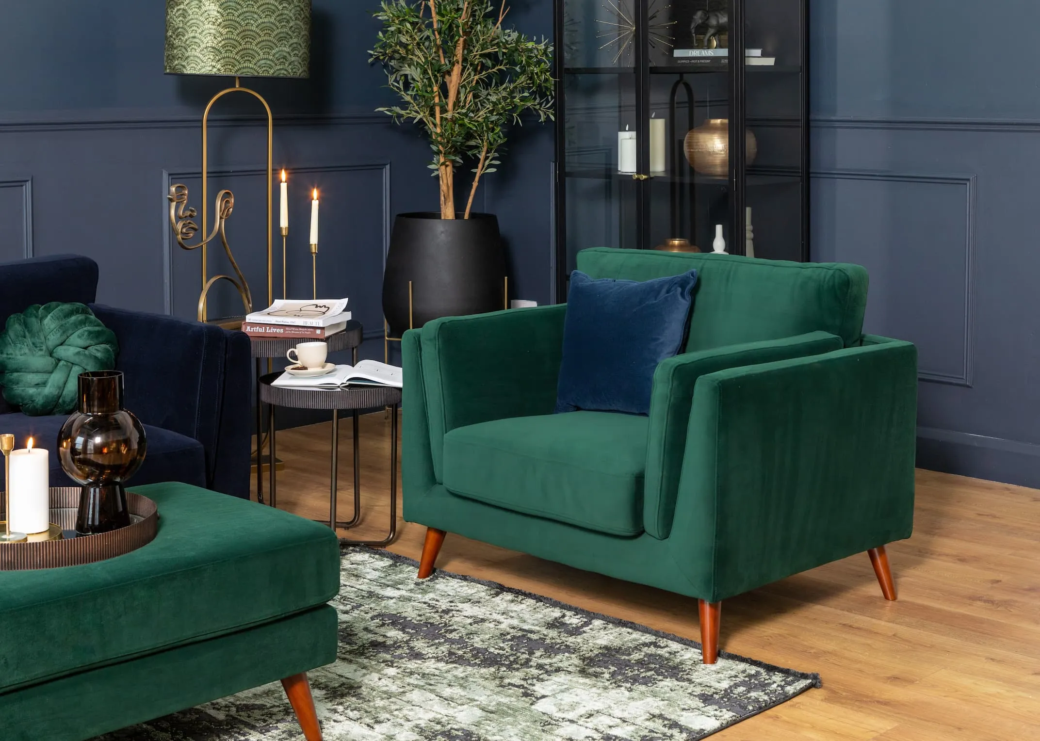 A lifestyle image of the Bellini green armchair with footstool and Carmel display unit
