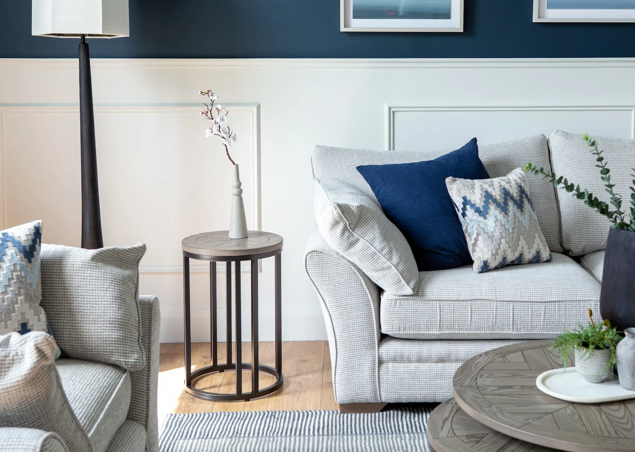 A lifestyle image of the Strat Sofa with Monrow side table with vase and Jovany floor lamp.