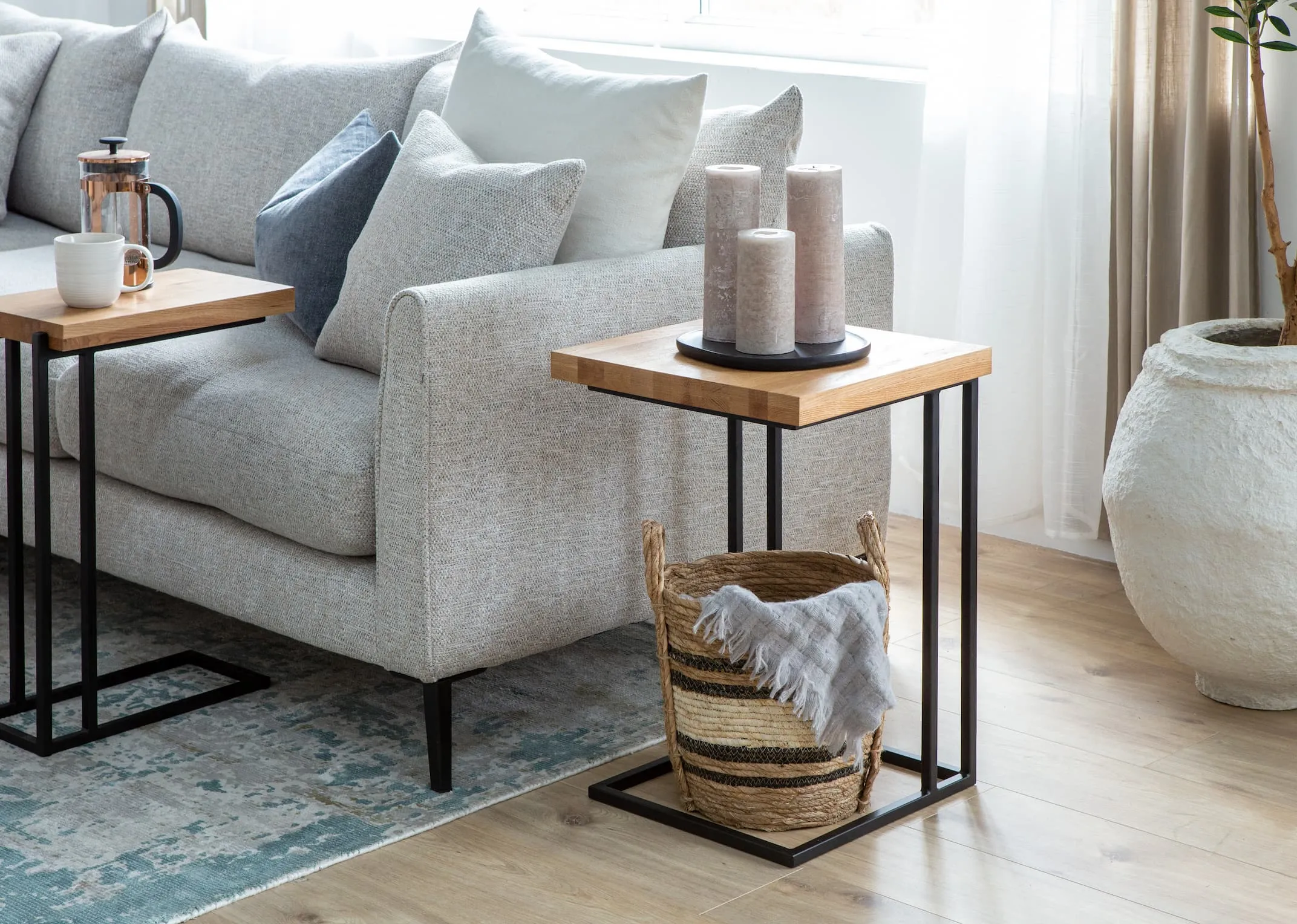 A lifestyle image of the Renvyle Wide Side table with tray & candles and room for a basket underneath paired with the Hunter sofa