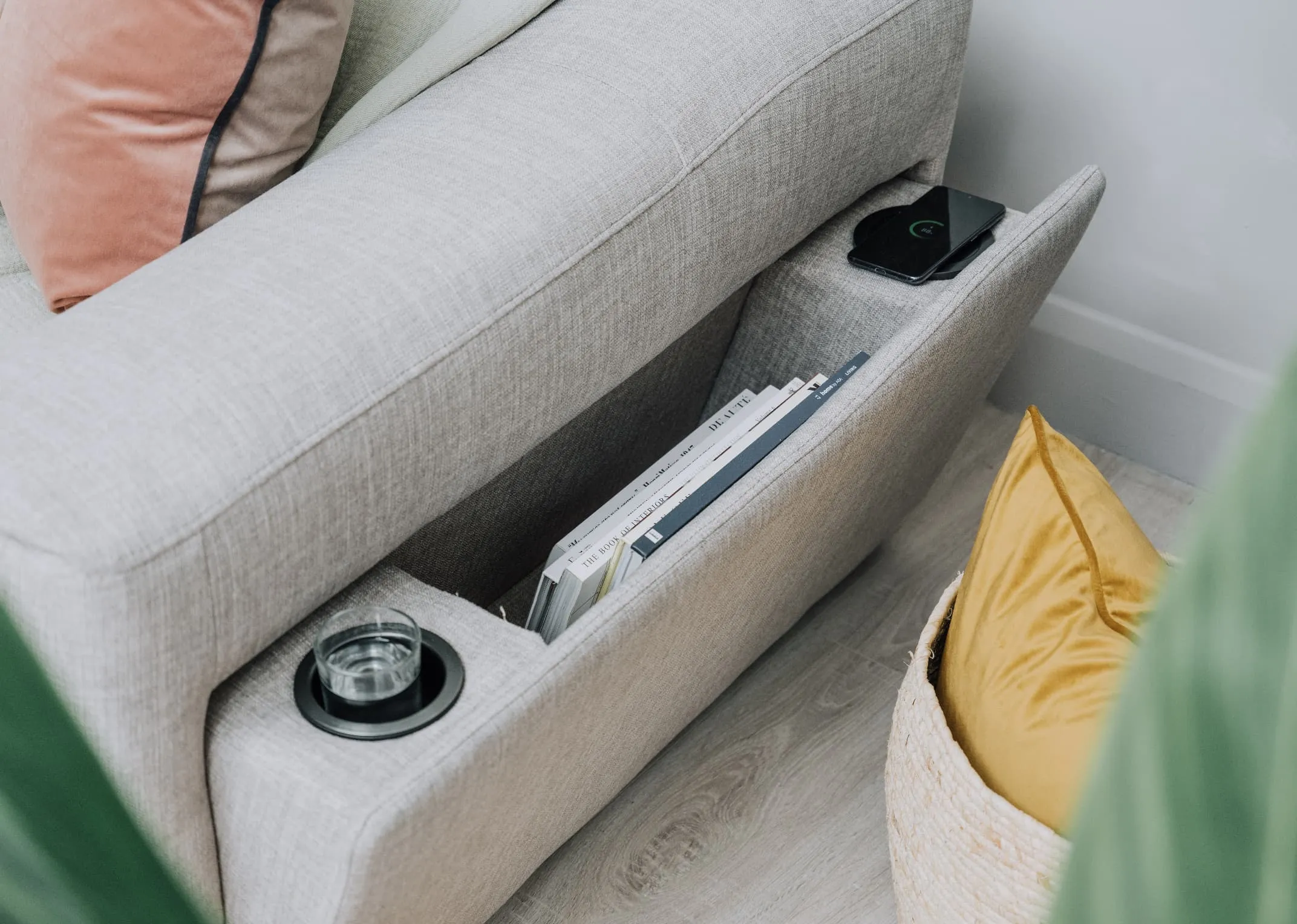 A lifestyle image of the Murano sofabed with side compartment open with glass holder books storage and phone charging.