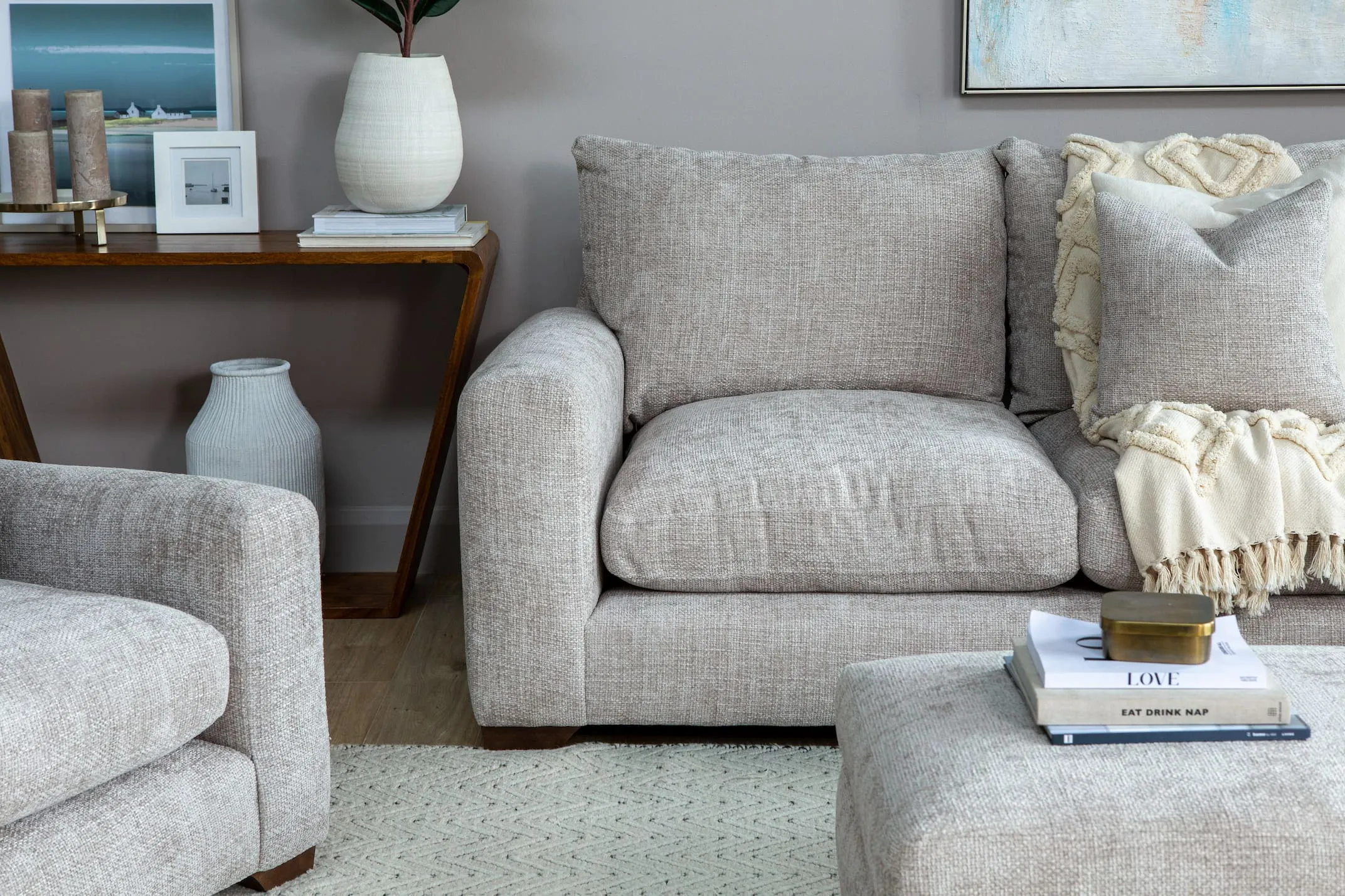 A lifestyle image of the Beige Fabric 1 arm 2 seater LHF corner unit paired with the Capri console and Calvin rug