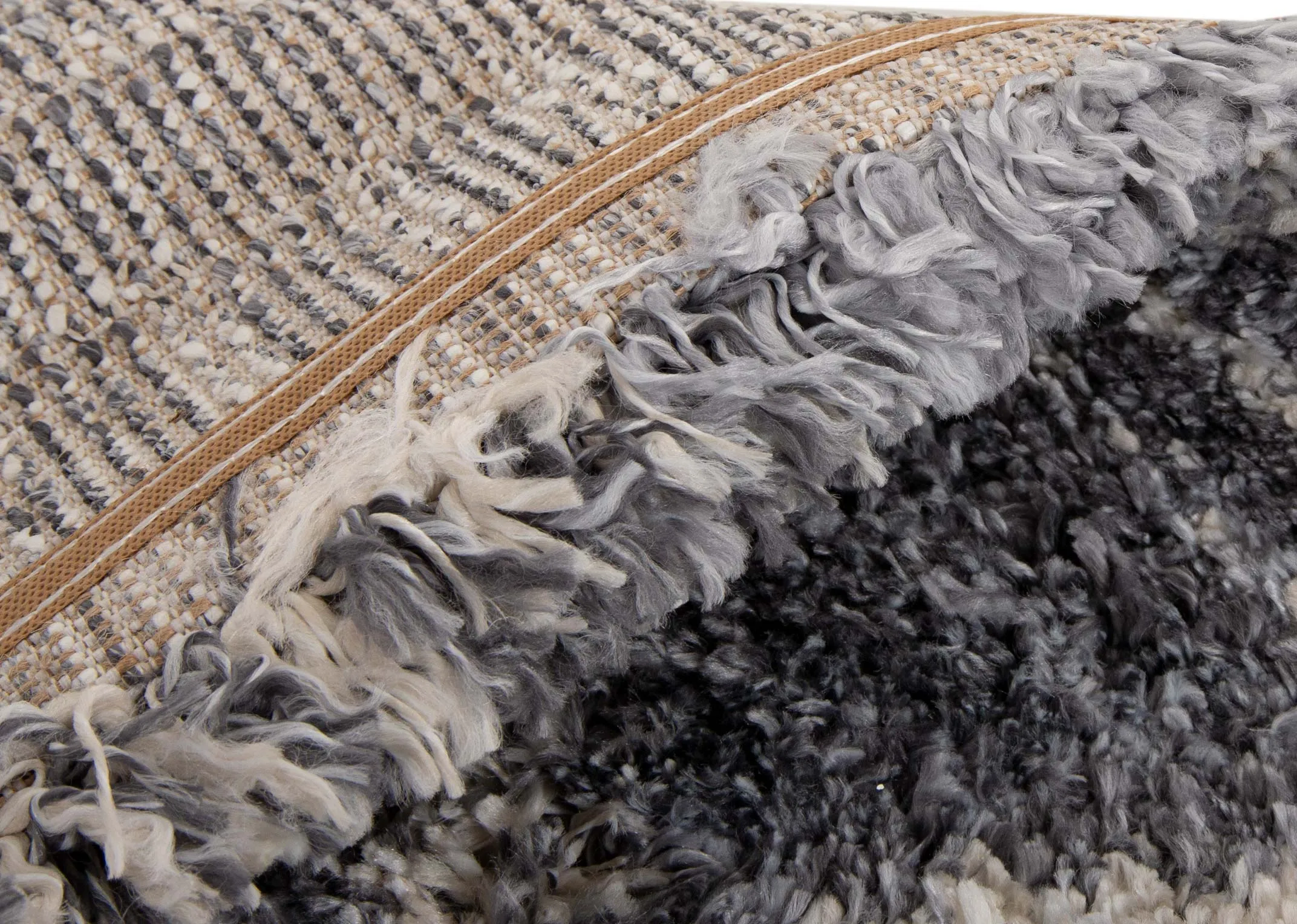 A dark grey deep pile rug with white Aztec print from EZ Livings Sula range. Angled view