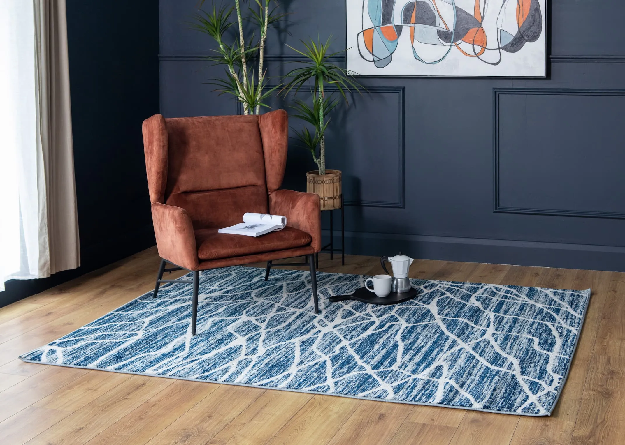 A lifestyle image of the Boston chair in rust with Grotto navy rug with corazo pots