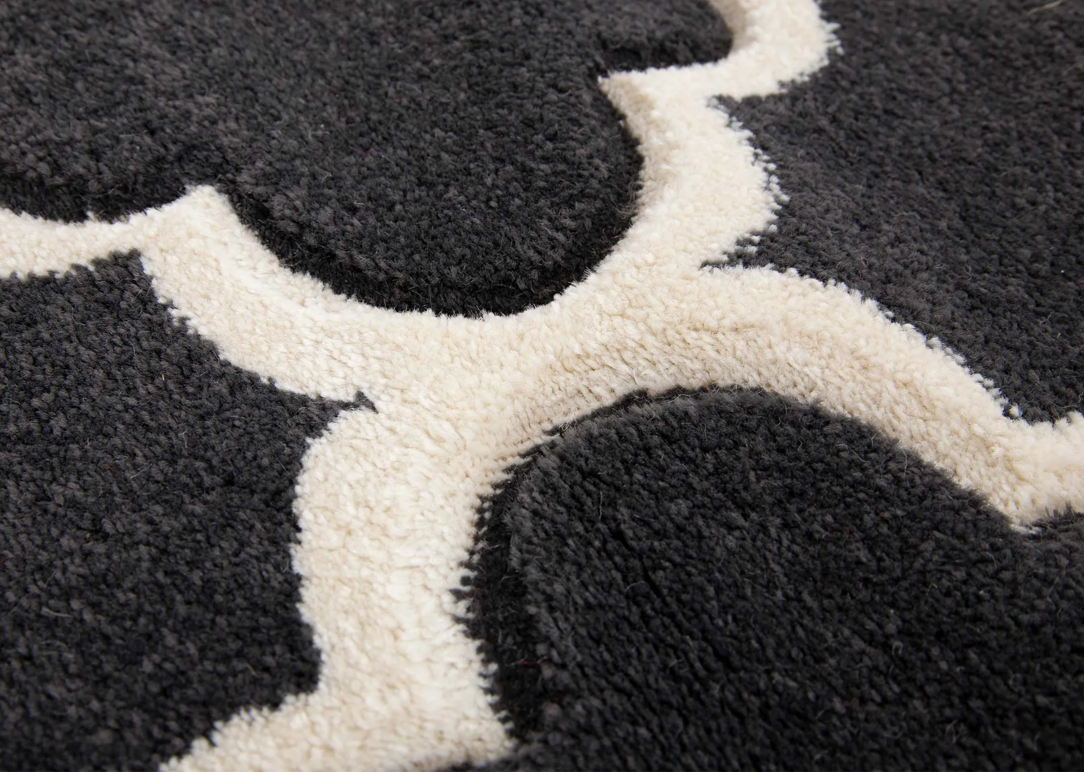 A dark grey rug with cream trellis design from EZ Livings Delia range. Closeup of soft to touch texture
