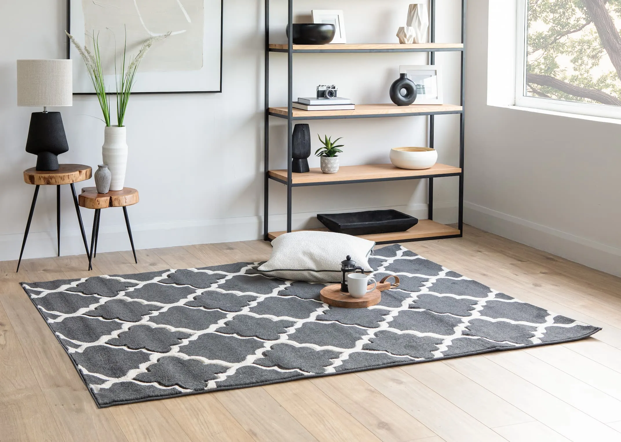 A lifestyle image of the Mila bookcase with capri tables and the Delia grey rug with a selection of ornaments