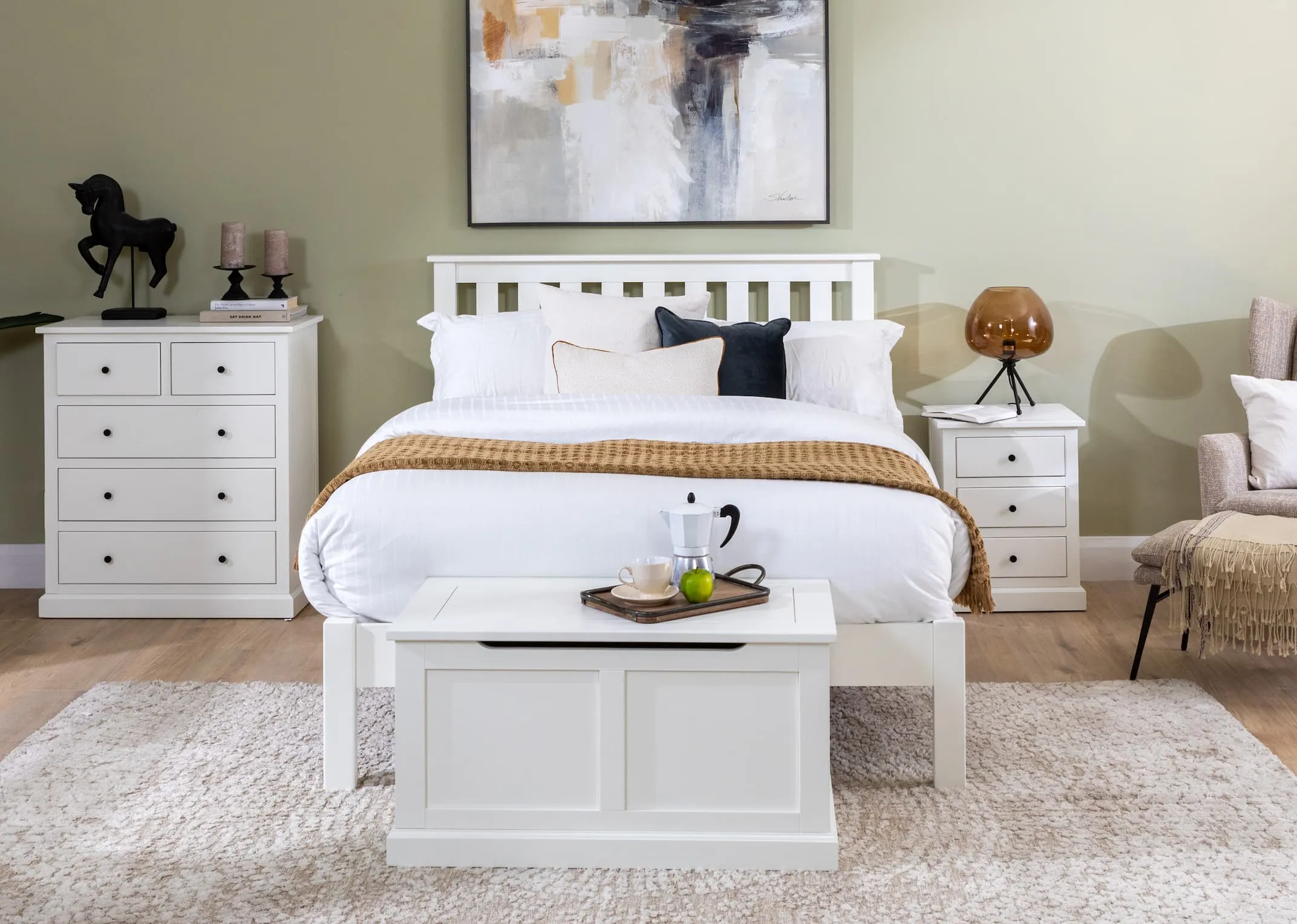 A lifestyle image of the White Atlas bedroom range including bedframe & chest of drawers & locker & blanket box with mayson lamp.