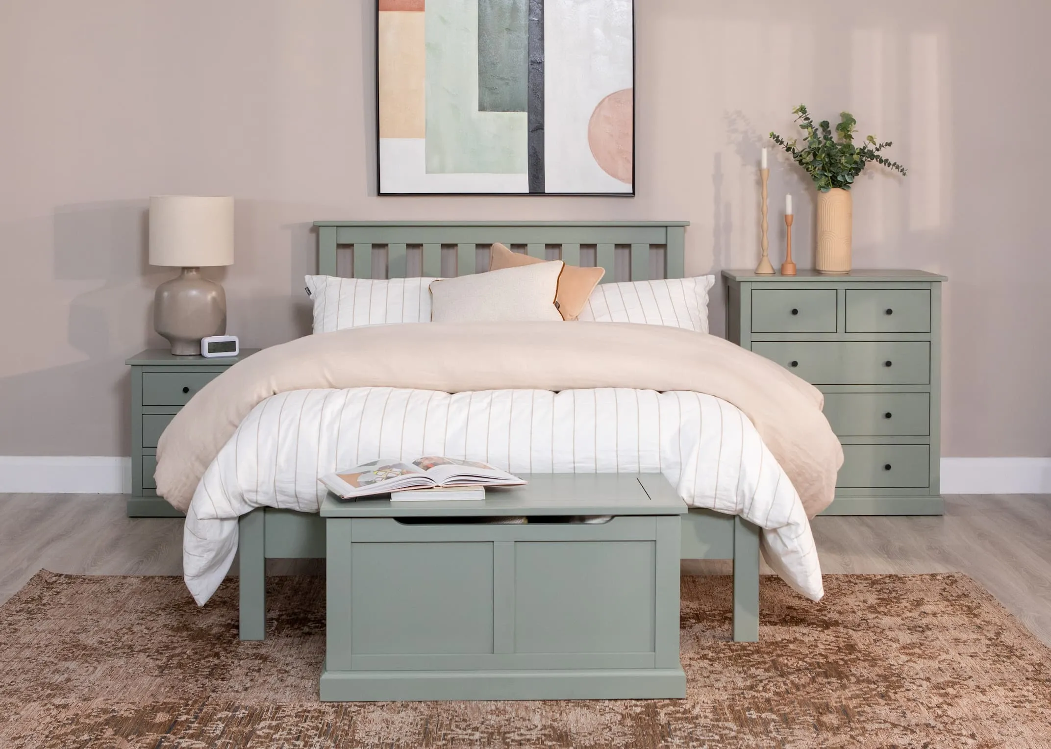 A lifestyle image of the Green Atlas locker with Retro lamp & the matching bedframe and blanket box from Atlas with the chest of drawers.