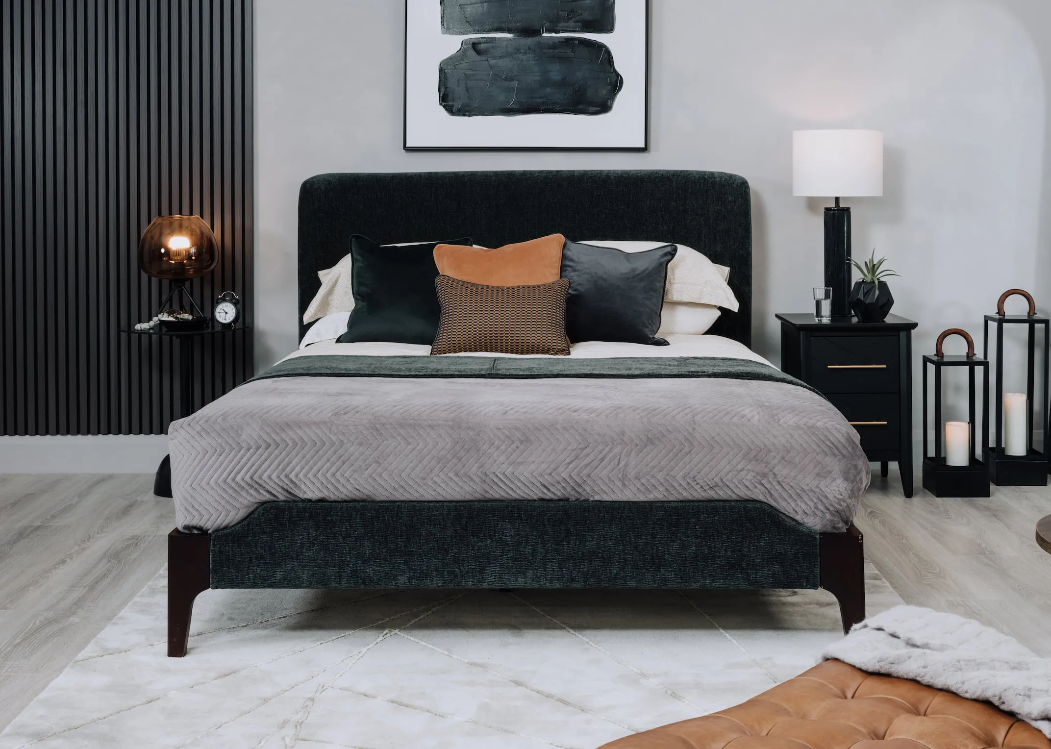 A lifestyle image of the Calm green bedframe with a selection of cushions and the chevron chest.
