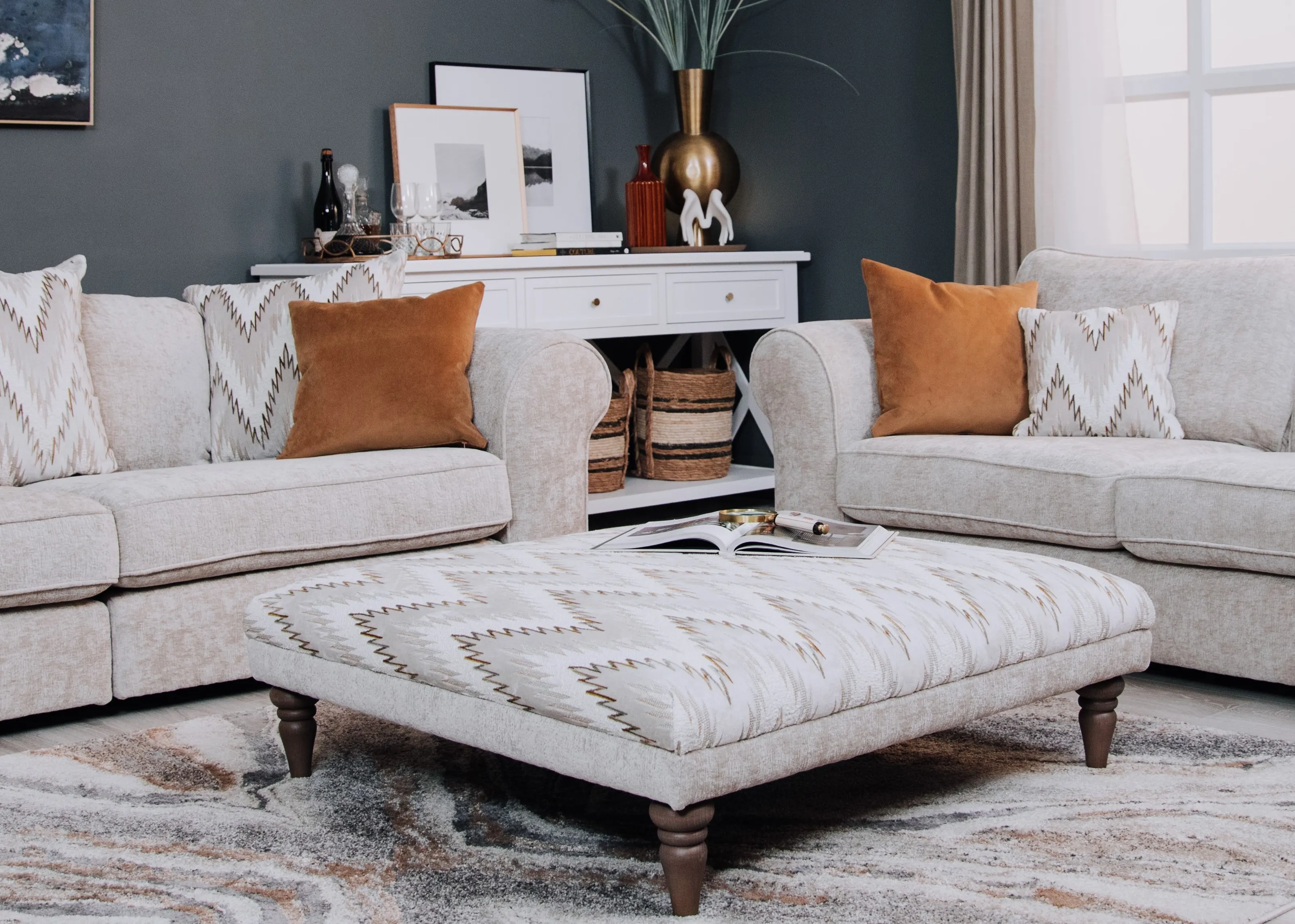 A lifestyle image of the Hayden Footstool with sofas and Aruba rug.