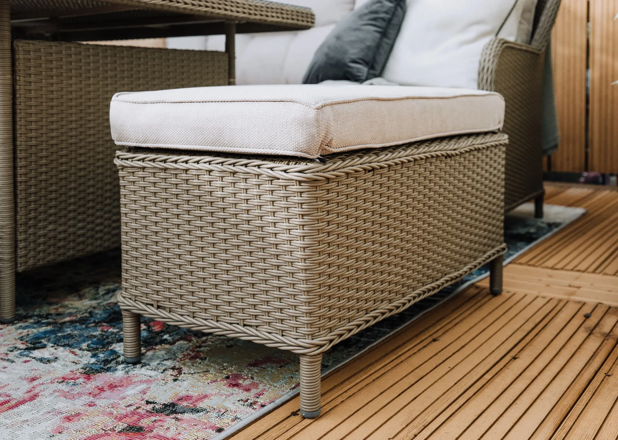 A wicker corner garden sofa with a square dining table & 2 ottoman benches from EZ Livings Marbella range. Front view of curved armrests on either end.