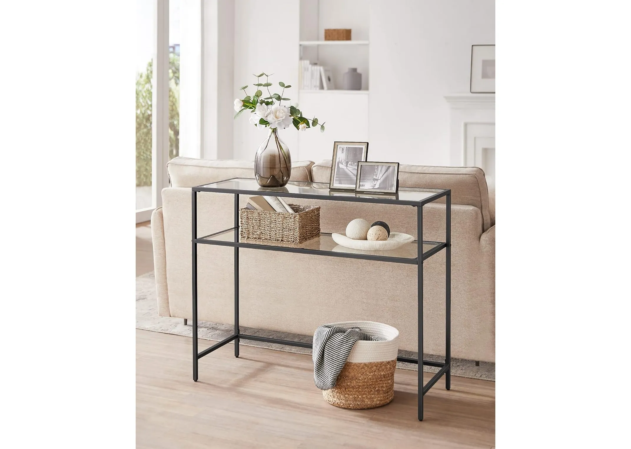 A black metal console table with glass shelves from EZ Livings Zafon range. Front  view shows lots of space beneath the shelves.